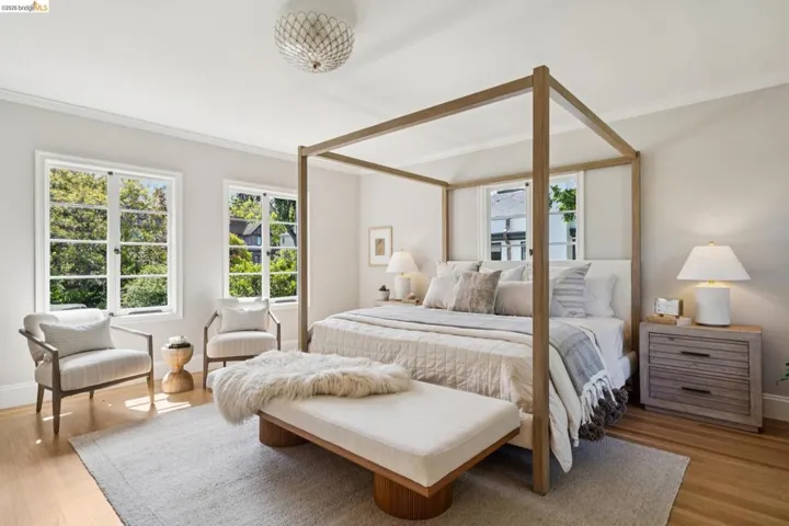 Hardwood flooring throughout featuring two large windows, crown molding, and a decorative ceiling light fixture