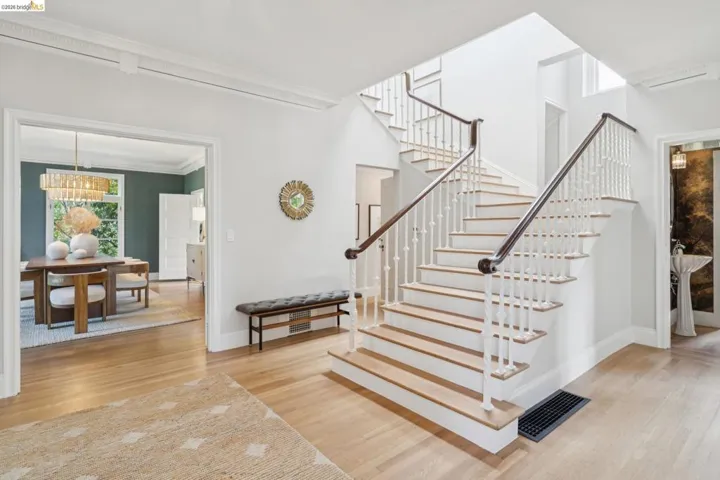 Grand foyer featuring a bifurcated staircase with wood-finish treads and white balusters