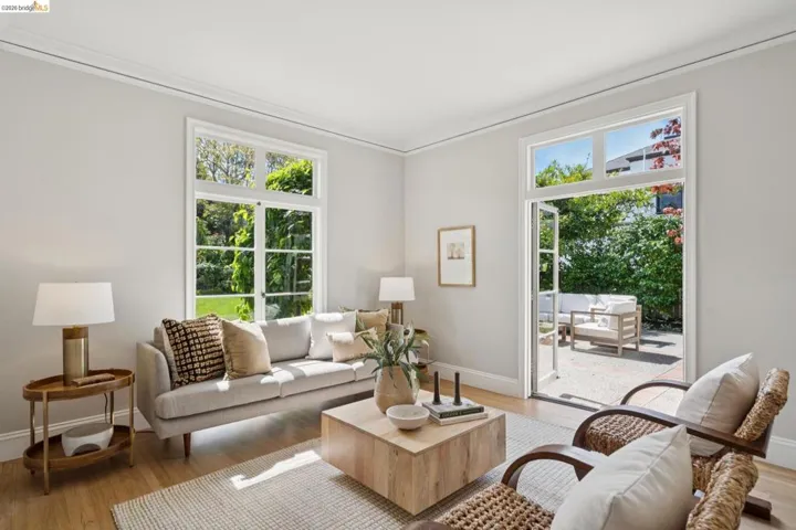 Bright living space featuring natural light, wood-finish flooring, white crown molding, and direct access to an outdoor patio area