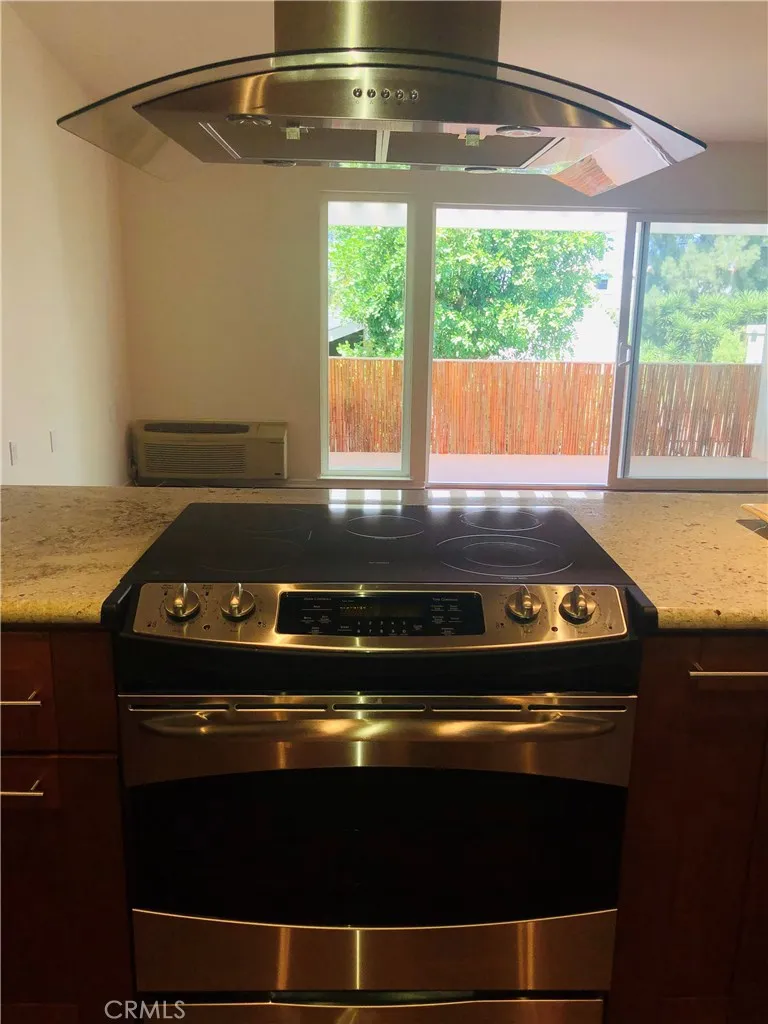 Contemporary range and hood with glass accents looks out to patio (some prior photos from listing used, fence lattice since removed)