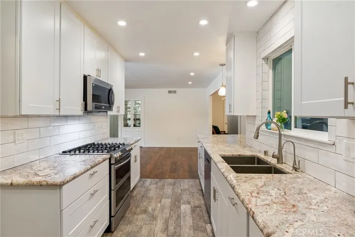 The kitchen features a timeless subway tile backsplash and wood looking ceramic tile floors.