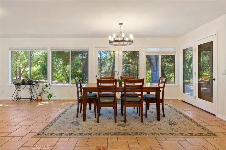 The dining area features a modern chandelier and French doors that lead out to the backyard.