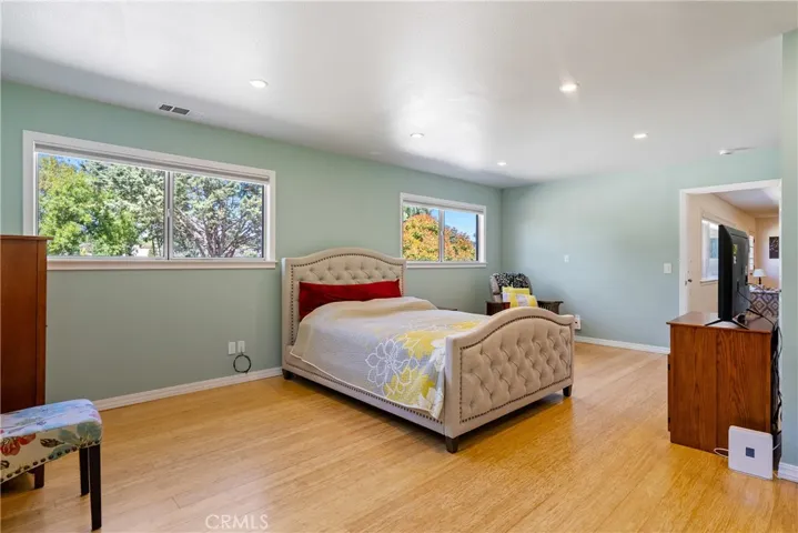 Multiple windows flood the room with natural light. The primary bedroom  also offers bamboo floors and recessed lights.
