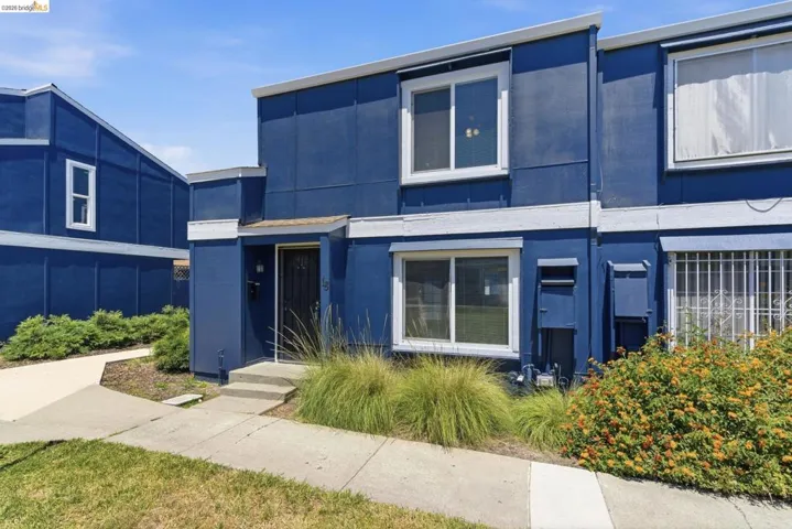 Multi-story exterior featuring a vibrant blue facade, white trim accents, and a dark entry door