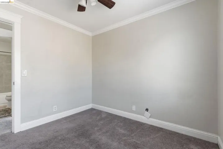 Neutral gray wall finish with crown molding and white baseboards