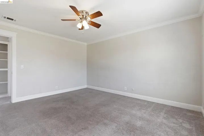 Neutral-toned interior room featuring crown molding and baseboards