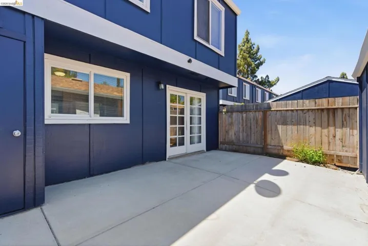 Private concrete patio space featuring a solid wood fence