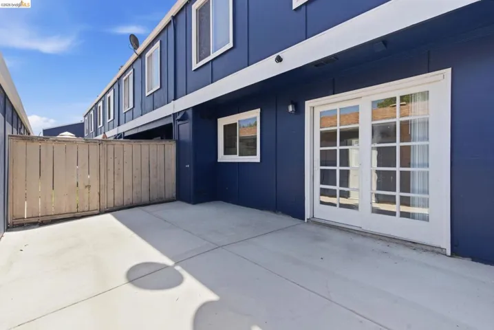 Paved patio area featuring privacy fencing and white-framed French doors
