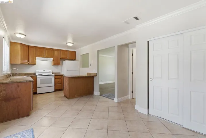 Kitchen featuring wood cabinetry, white appliances, and a breakfast bar with a stone-finish countertop