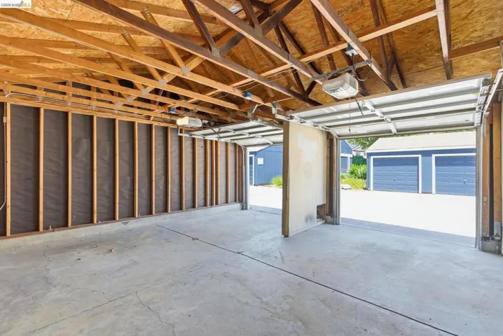 Spacious two-car garage with concrete flooring, exposed wood beam ceiling, and two overhead garage door openers