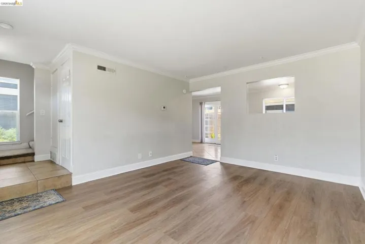 Spacious interior featuring wood-finish flooring, light grey painted walls, white crown molding, and white baseboards