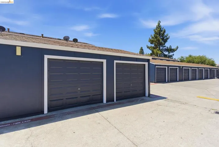 Multiple dark gray garage doors with white trim, set against a dark blue exterior siding