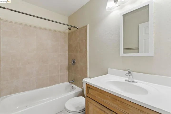 Bathroom featuring a white vanity with an integrated sink, chrome faucet, and wood-finish cabinetry