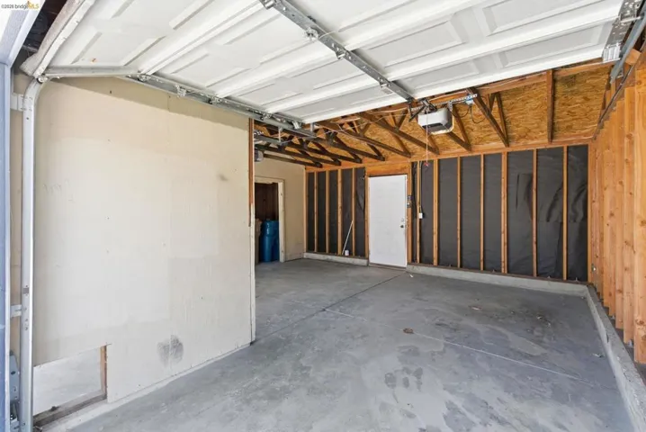 Spacious garage featuring a concrete floor, exposed wood framing, and an overhead garage door