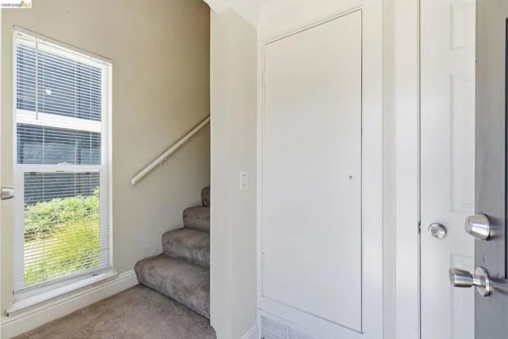 Entryway featuring a white paneled door, chrome door hardware, and a window with white blinds