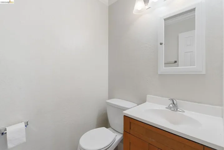 Bathroom featuring a wood-finish vanity with an integrated sink, white medicine cabinet, and wall-mounted light fixture