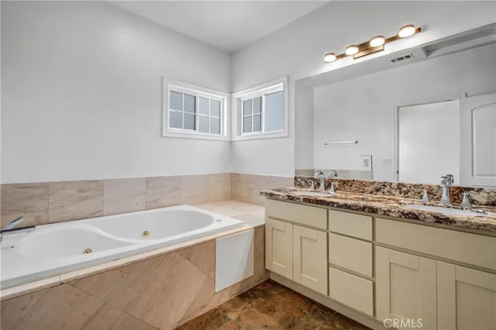 Primary bathroom with dual vanities and jacuzzi tub.