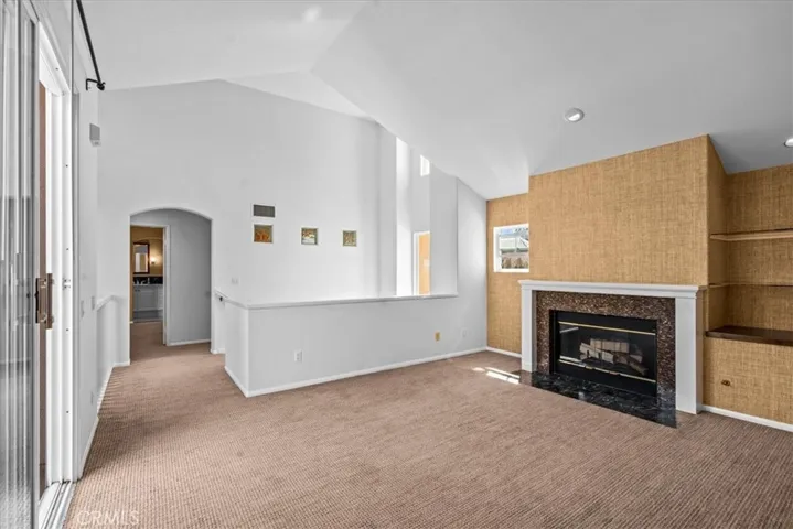 Living room with gas fireplace, vaulted ceilings and designer grass cloth wall treatment, gas fireplace and shelving