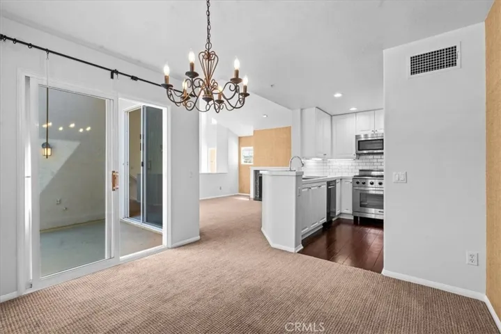 View from dining area to outdoor patio deck, kitchen and living room