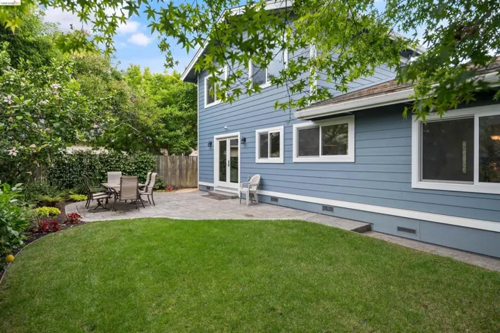 Expansive rear yard featuring a stone paver patio, lush lawn, and mature perimeter landscaping