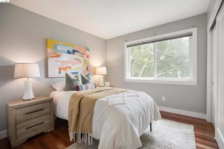 Bedroom featuring wood-finish flooring, a large window, light gray wall paint, and white trim