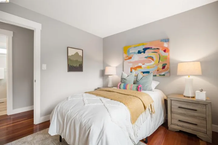 Bedroom featuring rich wood-finish flooring, light grey painted walls, and white trim