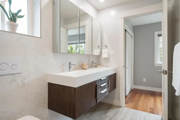 Modern bathroom featuring a floating dual vanity with integrated sinks, wood-finish cabinetry, and chrome fixtures