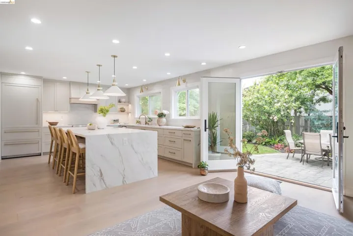 Gourmet kitchen with a waterfall island, integrated refrigerator, and light wood-finish flooring