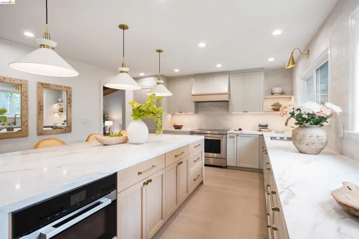 Kitchen featuring a large island with an integrated oven, white countertops, and light wood-finish flooring