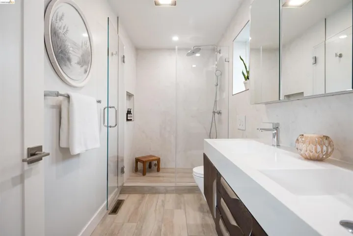 Contemporary bathroom featuring a dual-sink vanity with integrated white countertops and dark wood-finish cabinetry