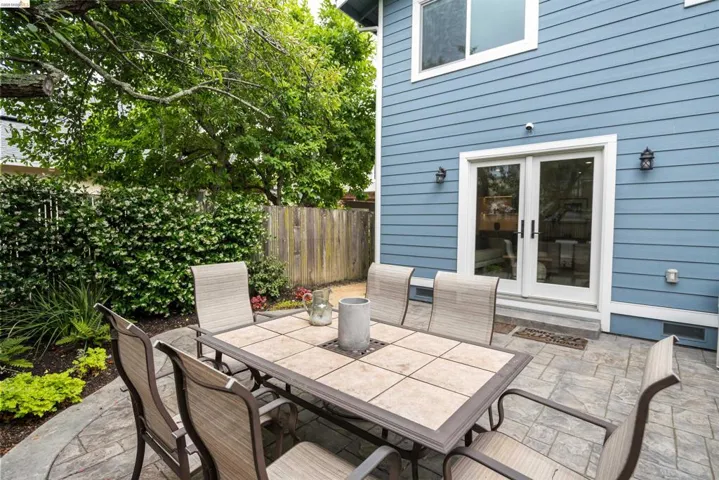 Outdoor patio featuring stamped concrete, mature perimeter landscaping, and direct access to the home via French doors