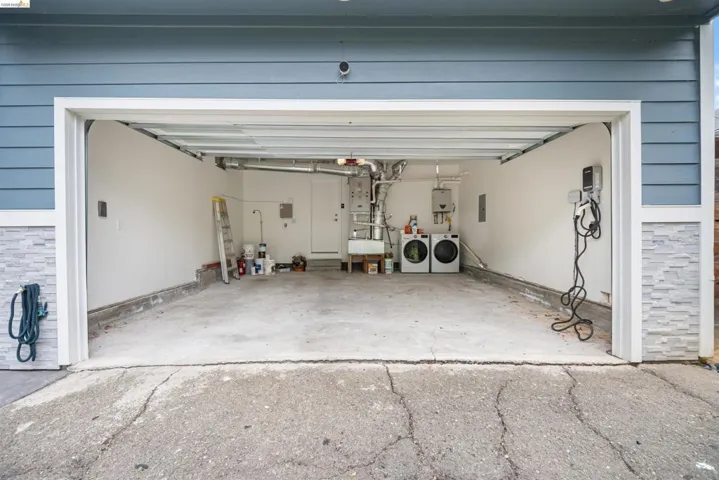 Garage interior featuring concrete flooring, white painted walls, and exposed utilities