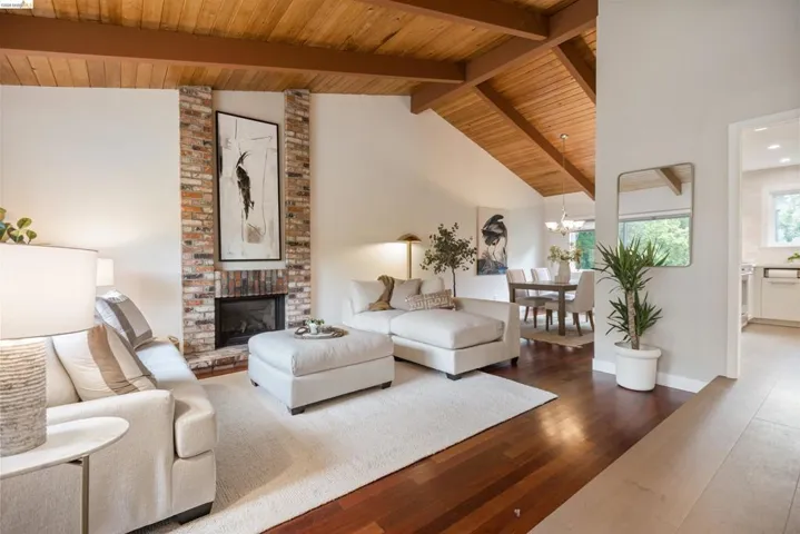 Living area featuring a vaulted wood-paneled ceiling, exposed wood beams, a brick fireplace, wood-finish flooring, and recessed lighting