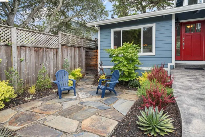 Front patio featuring flagstone paving, a wood privacy fence with lattice top, and varied mature landscaping