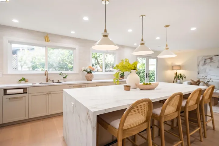 Waterfall island with seating for four, complemented by three pendant lights and recessed lighting