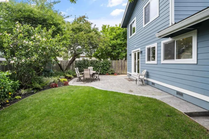 Expansive backyard featuring a manicured lawn, a paved patio, and mature trees