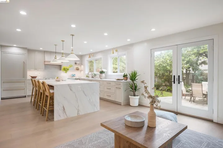 Open-concept kitchen featuring a waterfall island with integrated seating, recessed lighting, and light wood-finish flooring
