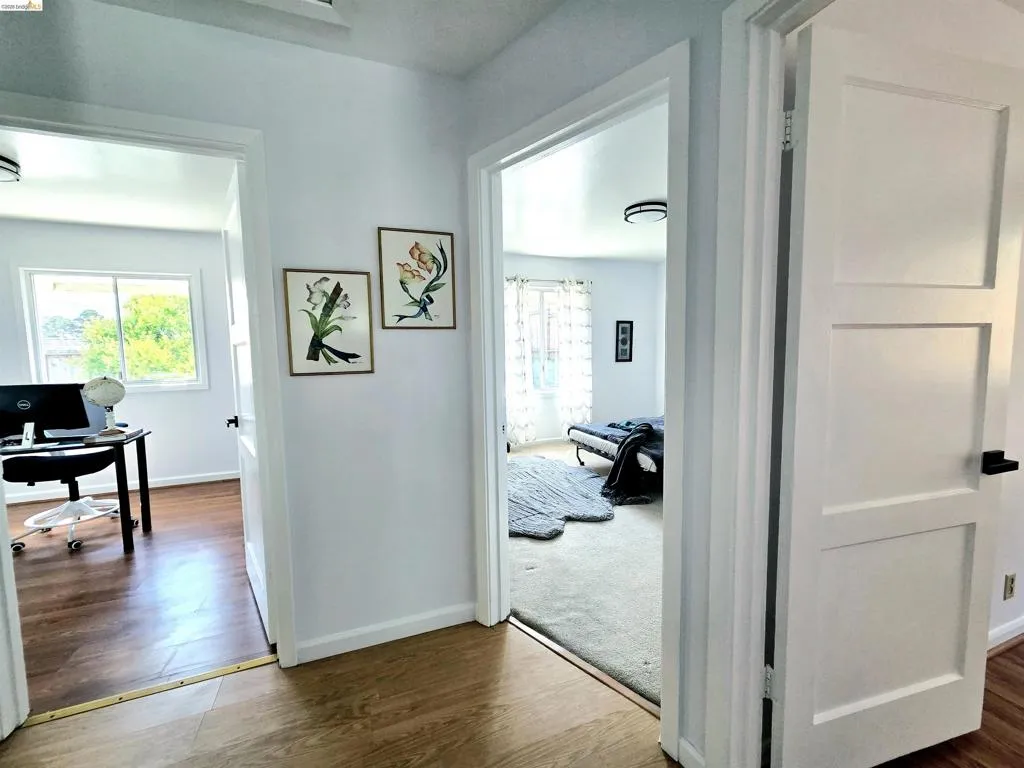 Hallway featuring wood-finish flooring, white walls, and modern flush-mount lighting fixtures
