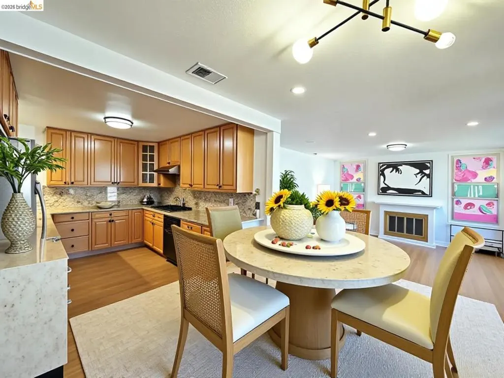 Open-concept dining area with a stone-finish table and wood-finish flooring. Virtual staging.