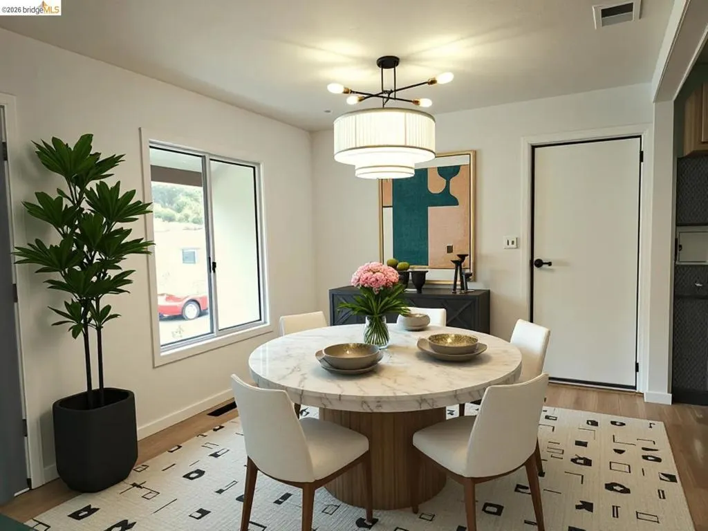 Bright dining area featuring a circular marble-top table, wood-finish flooring, and a contemporary chandelier. Virtual Staging.