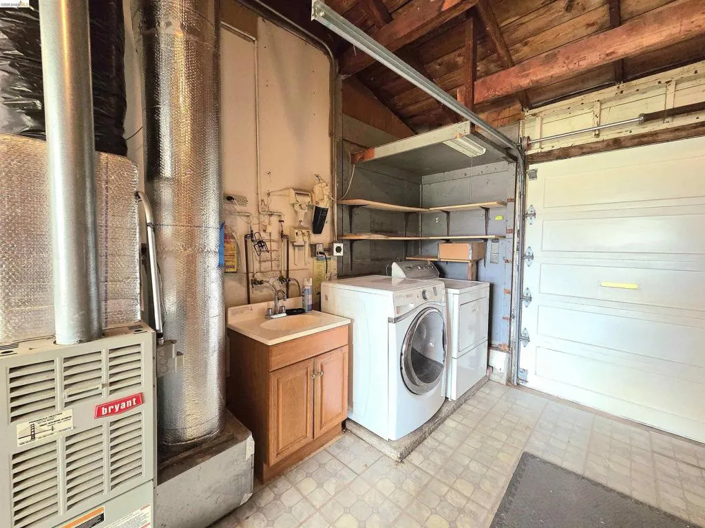 Utility area featuring a furnace, laundry hookups, and a built-in utility sink with cabinetry