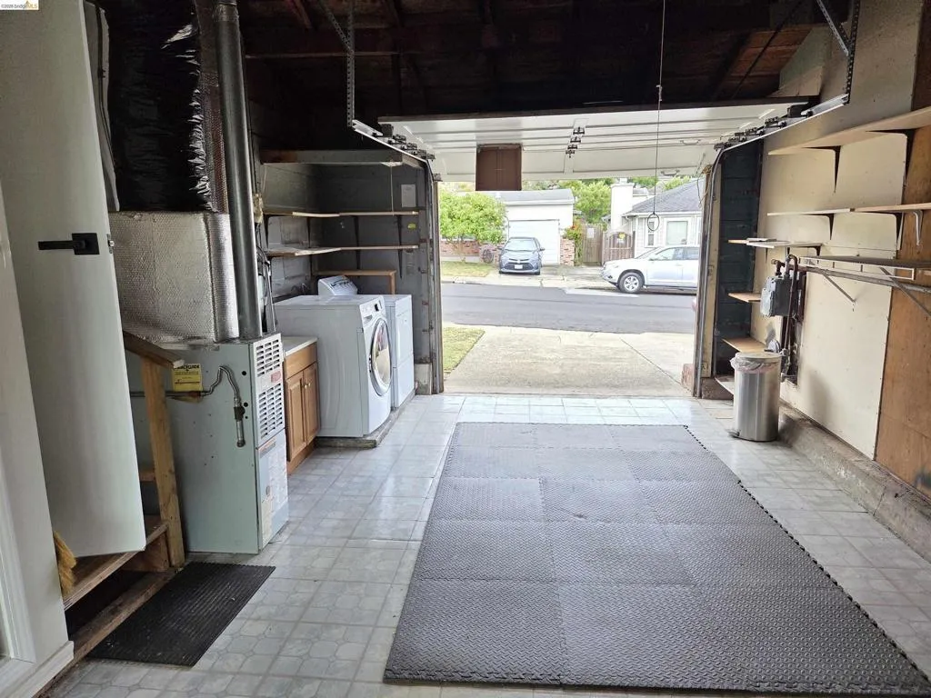 Garage interior featuring tile flooring, built-in shelving, a dedicated laundry area with a washer and dryer, and a built-in cabinet with a laminate countertop