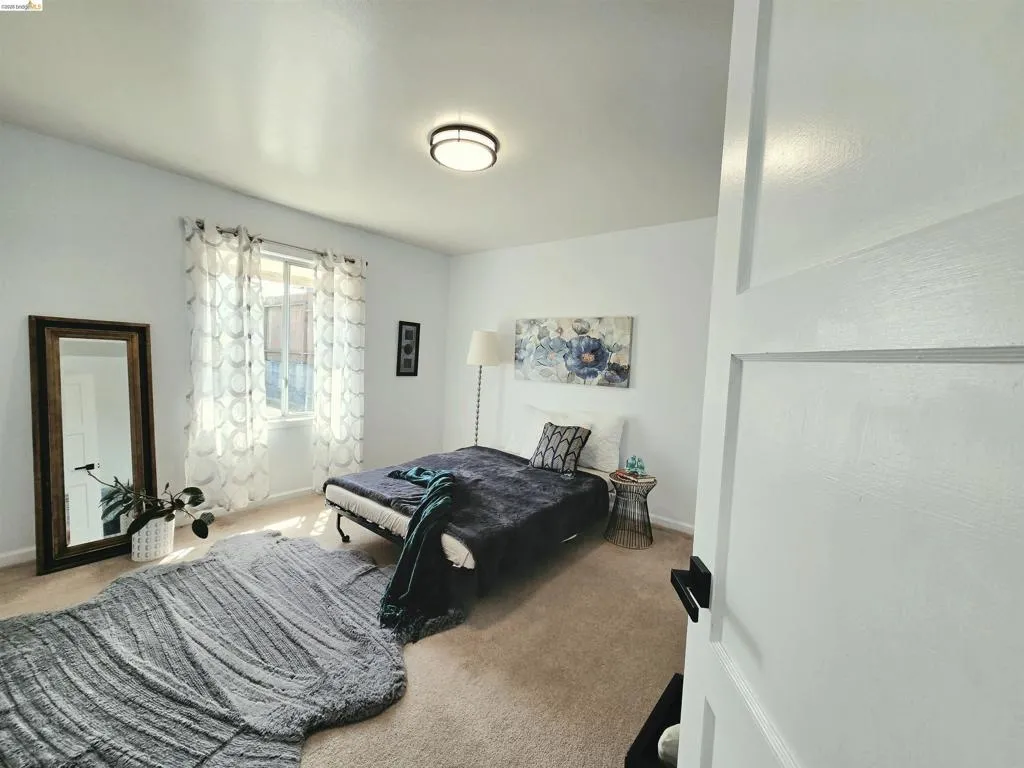 Carpeted room featuring a white paneled door with black hardware, a window with sheer curtains, recessed lighting, and white walls