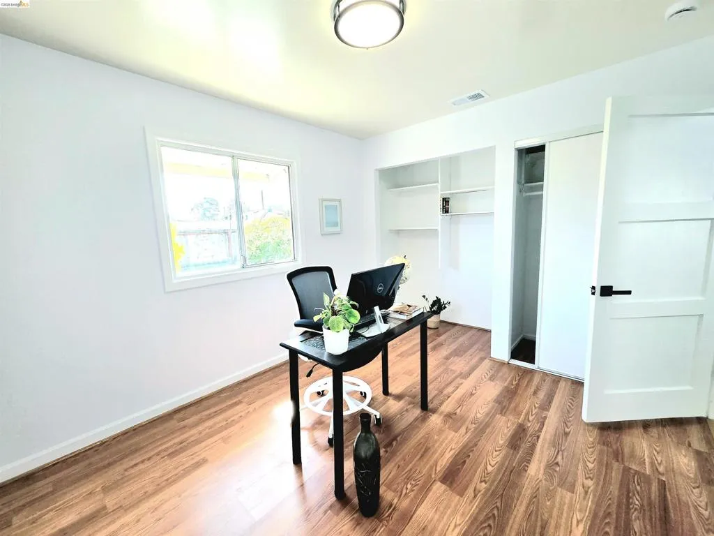 Room featuring wood-finish flooring, white walls, and a recessed window