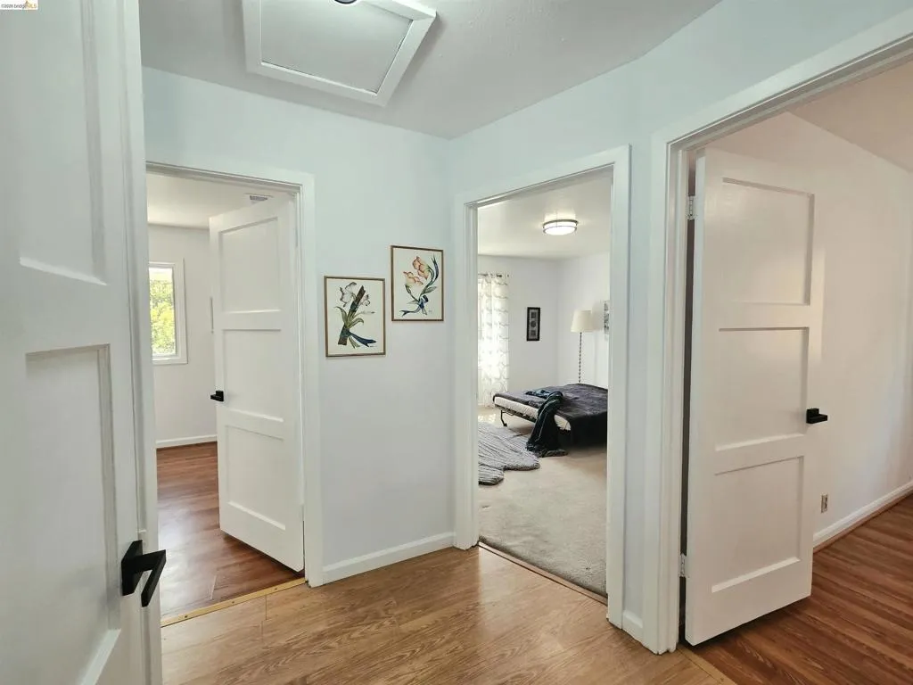 Hallway featuring recessed lighting, light wood-finish flooring, white baseboards, and white panel doors with matte black hardware