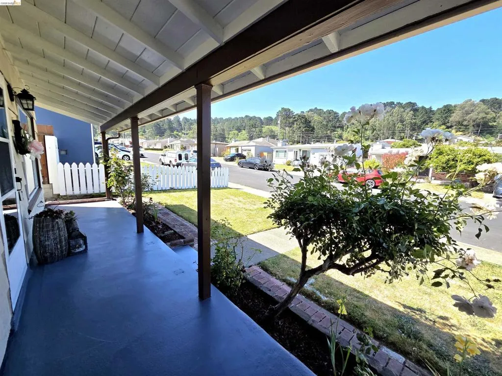 Covered front porch with a painted surface, supported by exposed wooden beams