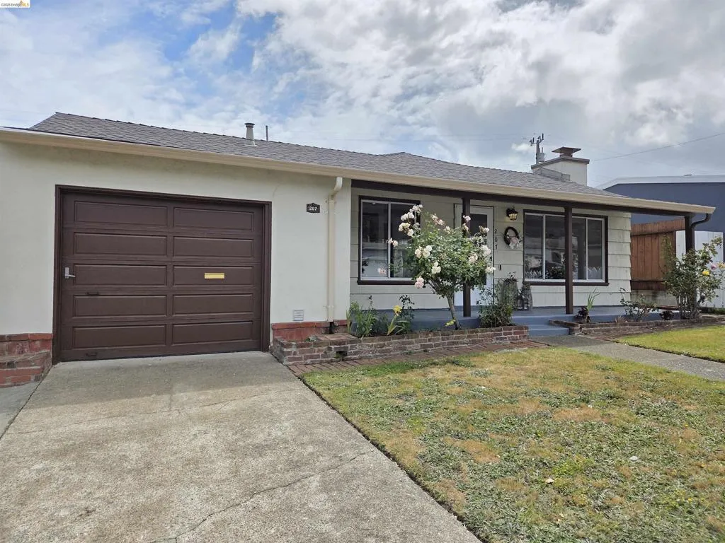 Single-story residence featuring a brown paneled garage door, a covered front porch, and a concrete driveway