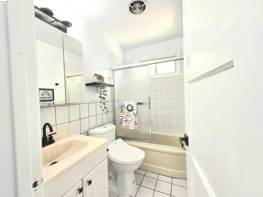 Bathroom with white square floor tiles, a white vanity cabinet, a sink with a matte black faucet, and a wall-mounted medicine cabinet