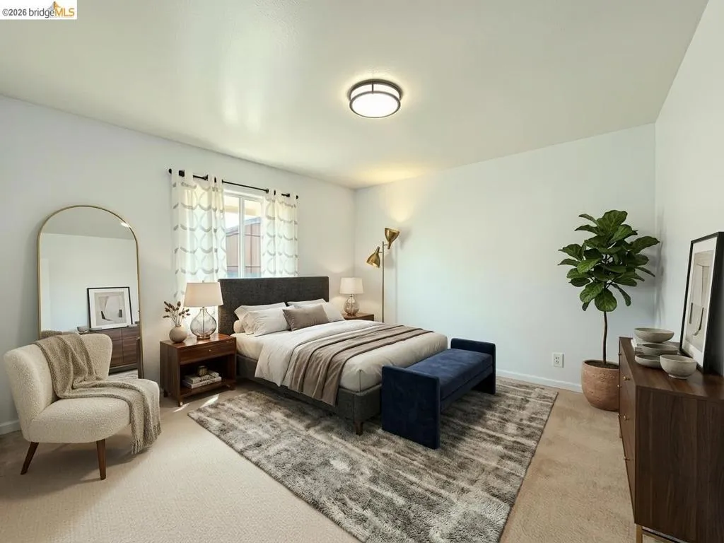 Spacious bedroom featuring light-colored carpeting, a window with natural light, and a ceiling-mounted light fixture. Virtual staging.