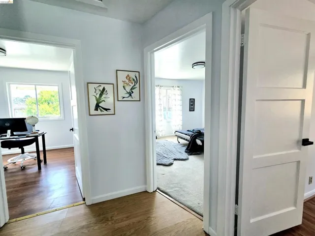 Hallway featuring wood-finish flooring, white walls, and modern flush-mount lighting fixtures